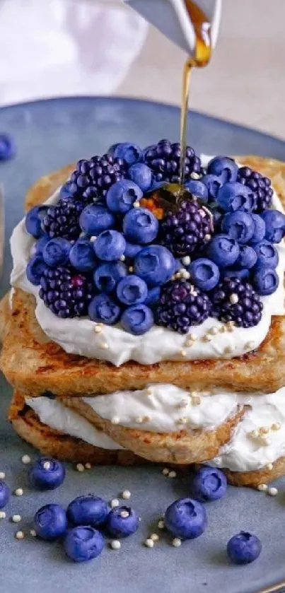 Blueberry pancakes with cream and syrup on a plate.