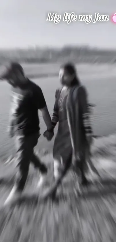 Blurred couple walking in grayscale, holding hands.