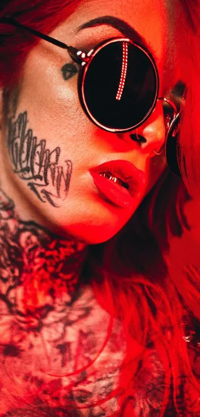 Stylish tattooed person with sunglasses in vibrant red light.