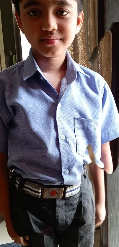 Young boy in blue school uniform with light background.