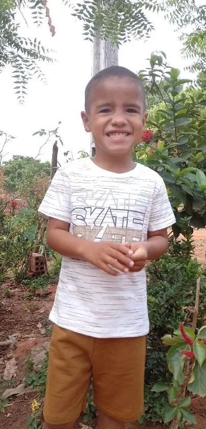 Smiling boy standing in a lush green garden.