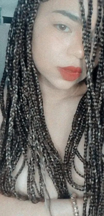 A woman with long, braided hair and red lips on a wallpaper.