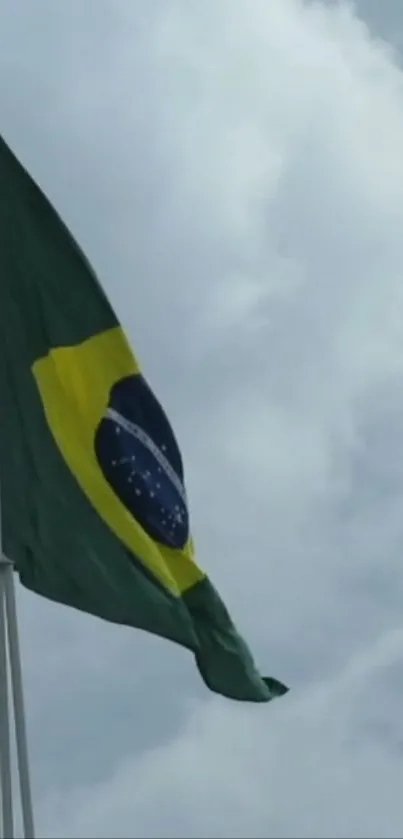 Brazilian flag waving under a cloudy sky on a flagpole.