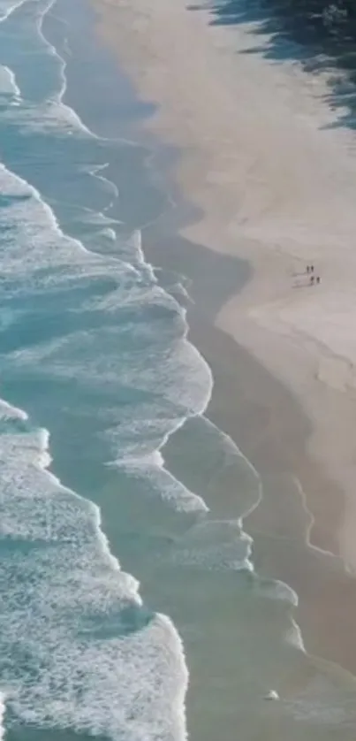 Aerial view of ocean waves meeting sandy beach.