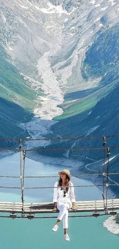 A scenic view of a woman on a suspension bridge overlooking a turquoise lake and mountains.