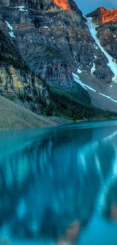 Mountain lake with clear water reflecting surrounding peaks at sunrise.