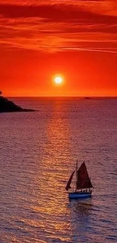 A beautiful red sunset over the ocean with a distant sailboat.