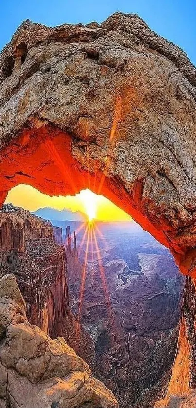 Sunrise through a natural rock arch with a canyon view.