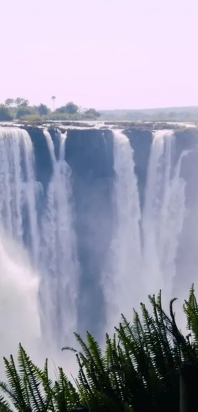 Majestic waterfall flowing into lush greenery background.