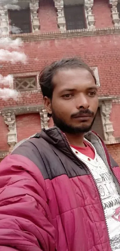 Outdoor selfie with a brick wall backdrop, showcasing rustic architecture.