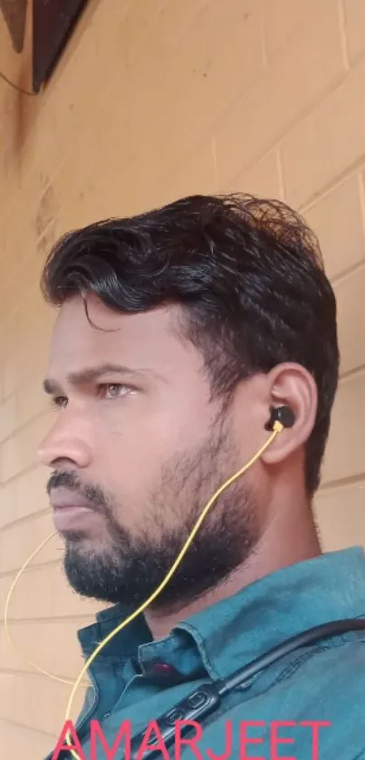 Side profile portrait with earphones against a brick wall.