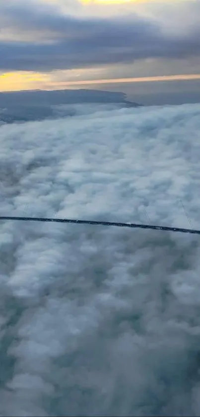 A bridge extends over a vast sea of fluffy clouds under a light blue sky at sunrise.