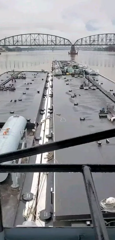 Cargo ship navigating under a steel arch bridge on a river.