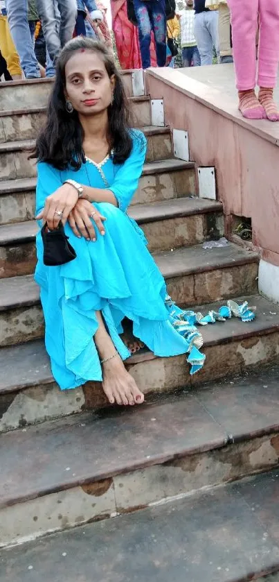 Woman in bright blue dress sitting on steps.