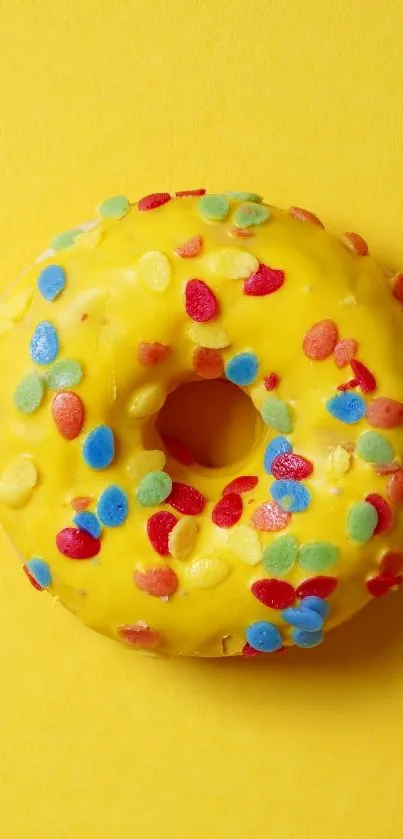 Bright yellow donut with colorful sprinkles on a matching background.