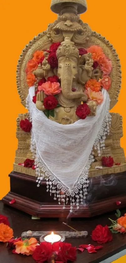 Ganesha statue on orange background with flowers.