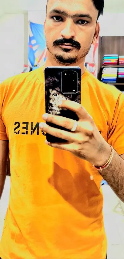 Mirror selfie with bright orange t-shirt showcasing modern fashion.