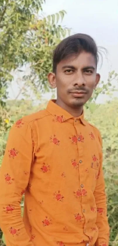 Person in bright orange shirt standing outdoors with green natural background.