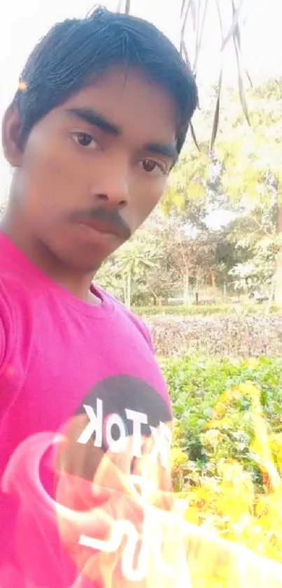 Selfie of young man in pink shirt outdoors.