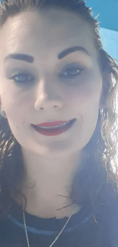 Smiling woman with curly hair against blue background.