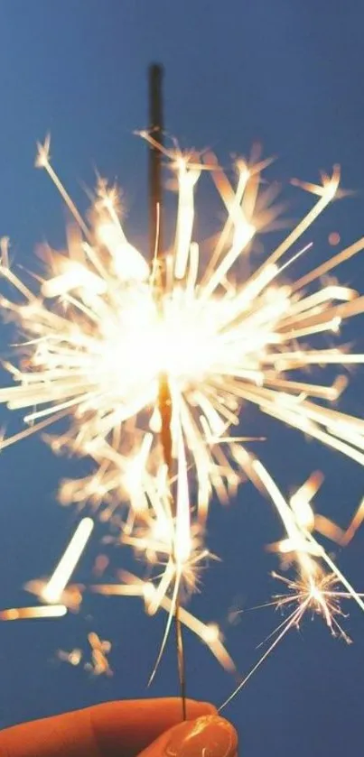 Sparkler in hand glowing against a blue night sky.