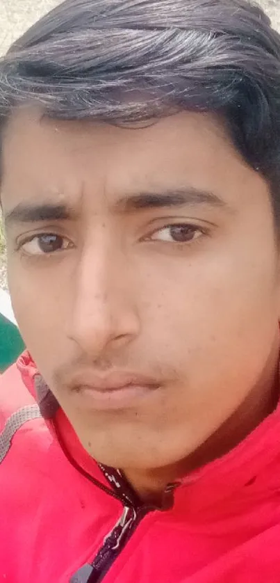 Young person takes a selfie on a park bench, wearing a bright red jacket.