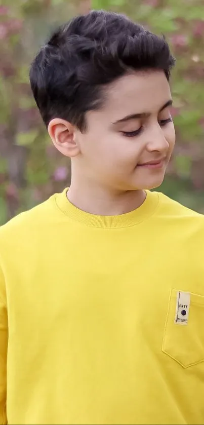 Young boy in bright yellow shirt with natural backdrop.