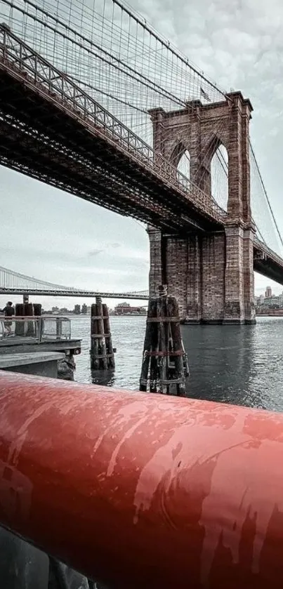 Brooklyn Bridge over calm river with city landscape.