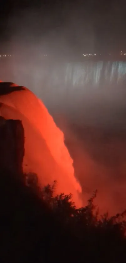 Fiery red waterfall glowing in misty nighttime scenery.