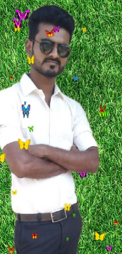 Man with sunglasses standing on grass surrounded by colorful butterflies.