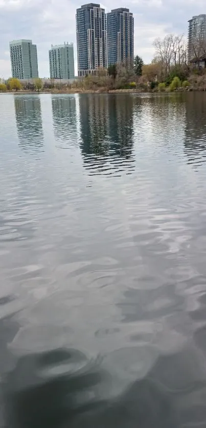 Serene lake with city skyline and reflections in calm waters.