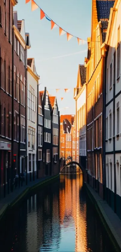 Canal street with hanging flags at sunset, reflecting orange hues.