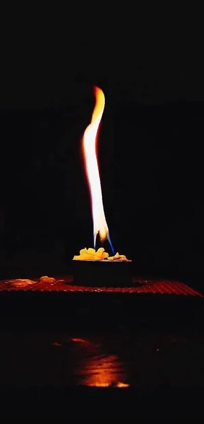 Candle flame glowing on a dark background.