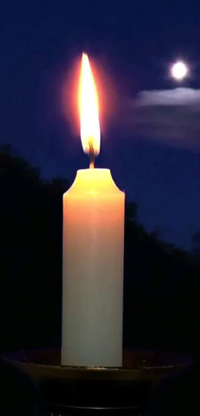 Candle glowing at night with moon in the background.