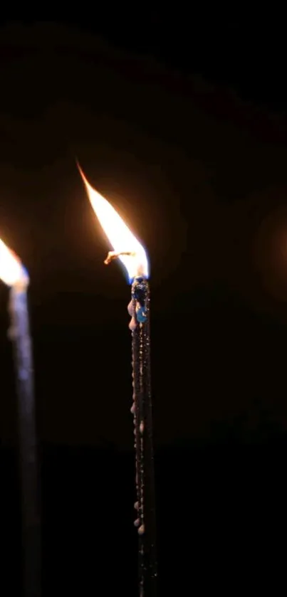 Close-up of candle flames glowing in the dark.