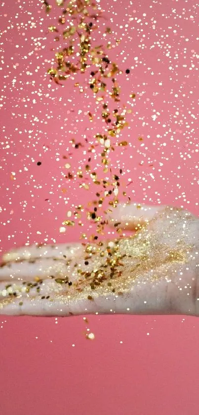 Hand releasing golden glitter against a pink background.