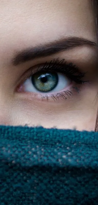 Close-up of a green eye, partially covered by teal fabric for phone wallpaper.