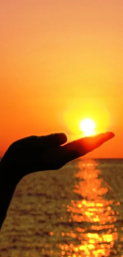 Beautiful orange sunset over ocean with hand silhouette.