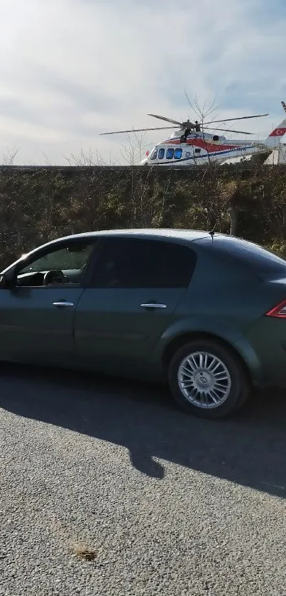 Gray car parked by roadside with helicopter in the sky.