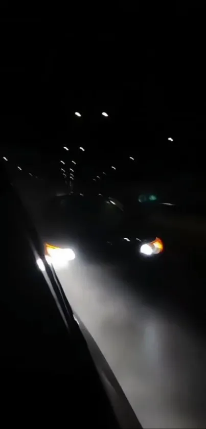 Car driving through a dark tunnel with headlights illuminating the path.