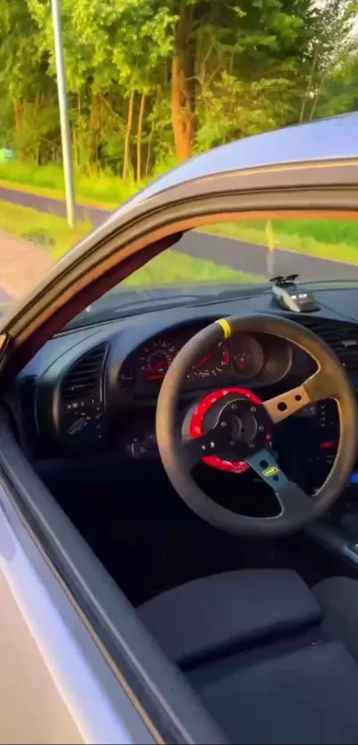 Car interior with red steering wheel in a scenic outdoor setting.