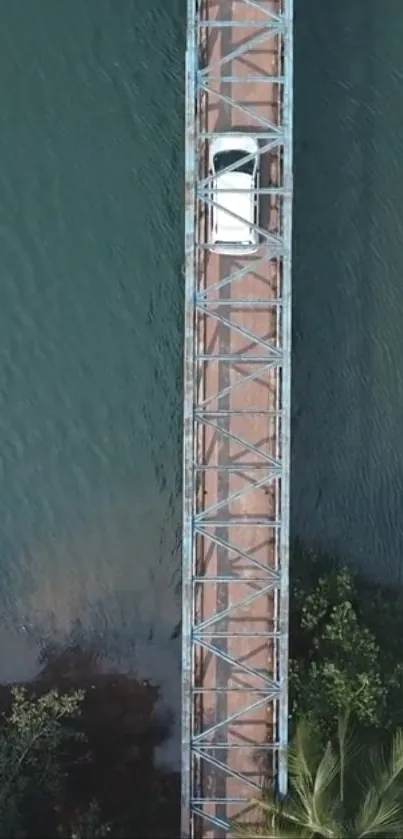 Aerial view of a car on a bridge over teal waters.