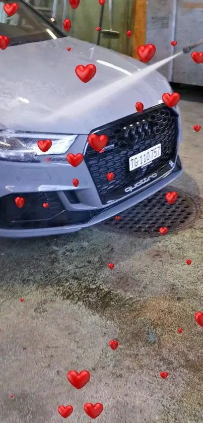 Gray car with red hearts design in a garage setting.