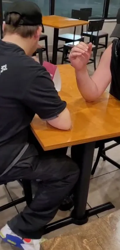 Casual arm wrestling in a café setting.