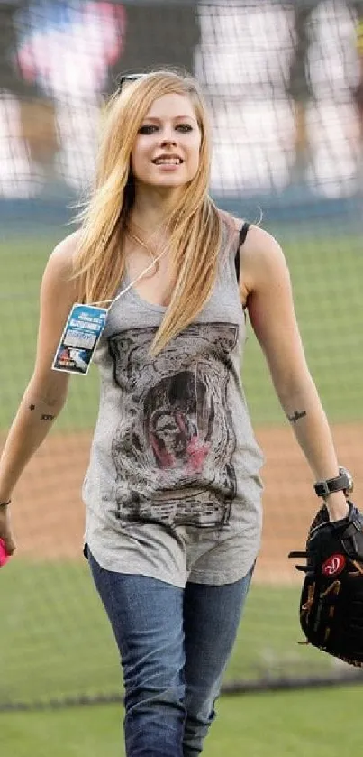 Woman in casual clothes on baseball field holding glove.