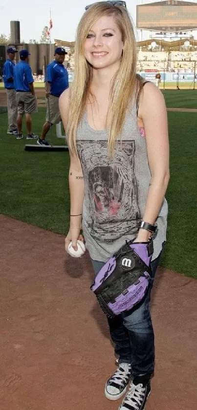 Person in casual attire at baseball field with green surroundings.