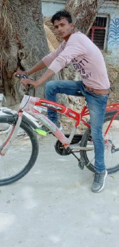 Young man on a bicycle in a casual setting with a natural backdrop.