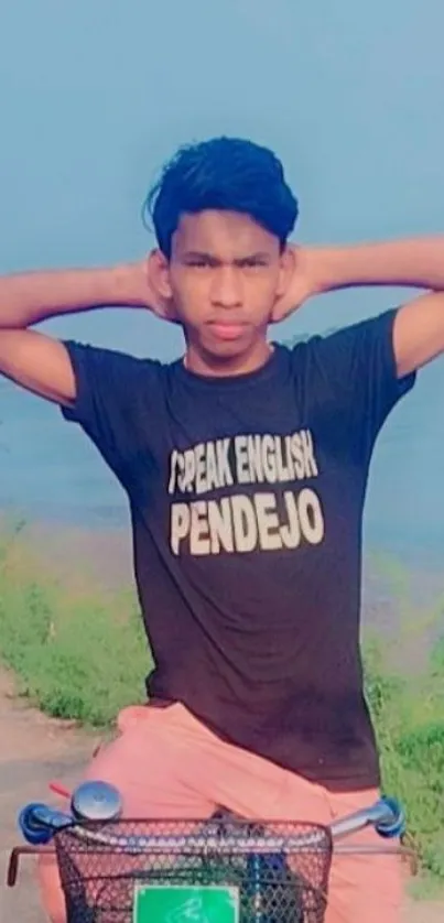 Young man posing with a bicycle by a scenic lakeside.