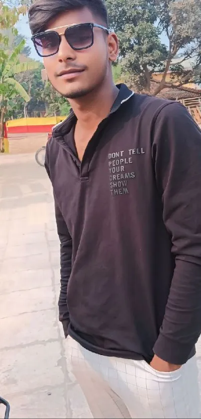 Young man in stylish black casual outfit with sunglasses outdoors.