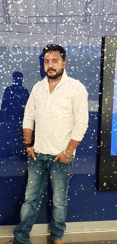 Man in white shirt and blue jeans standing casually against a blue background.